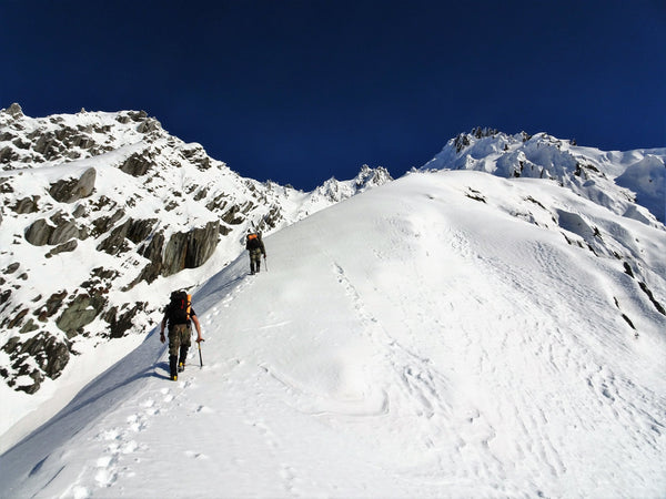 tahr hunters climbing a safe ridge line in the snow on a hot day